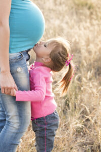 Child Kissing Baby in Mother's Tummy